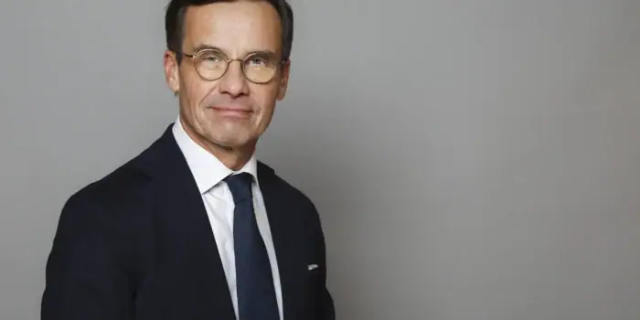 Porträtt i halvfigur på Ulf Kristersson mot grå bakgrund.