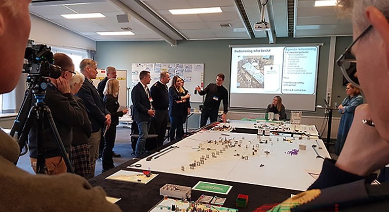 En grupp människor står runt ett stort bord. På bordet ligger en stor Gotlandskarta.